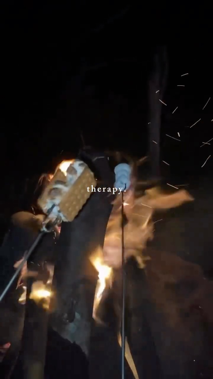 Hands roasting marshmallows over the La Cabaña campfire at night, sparks in the air